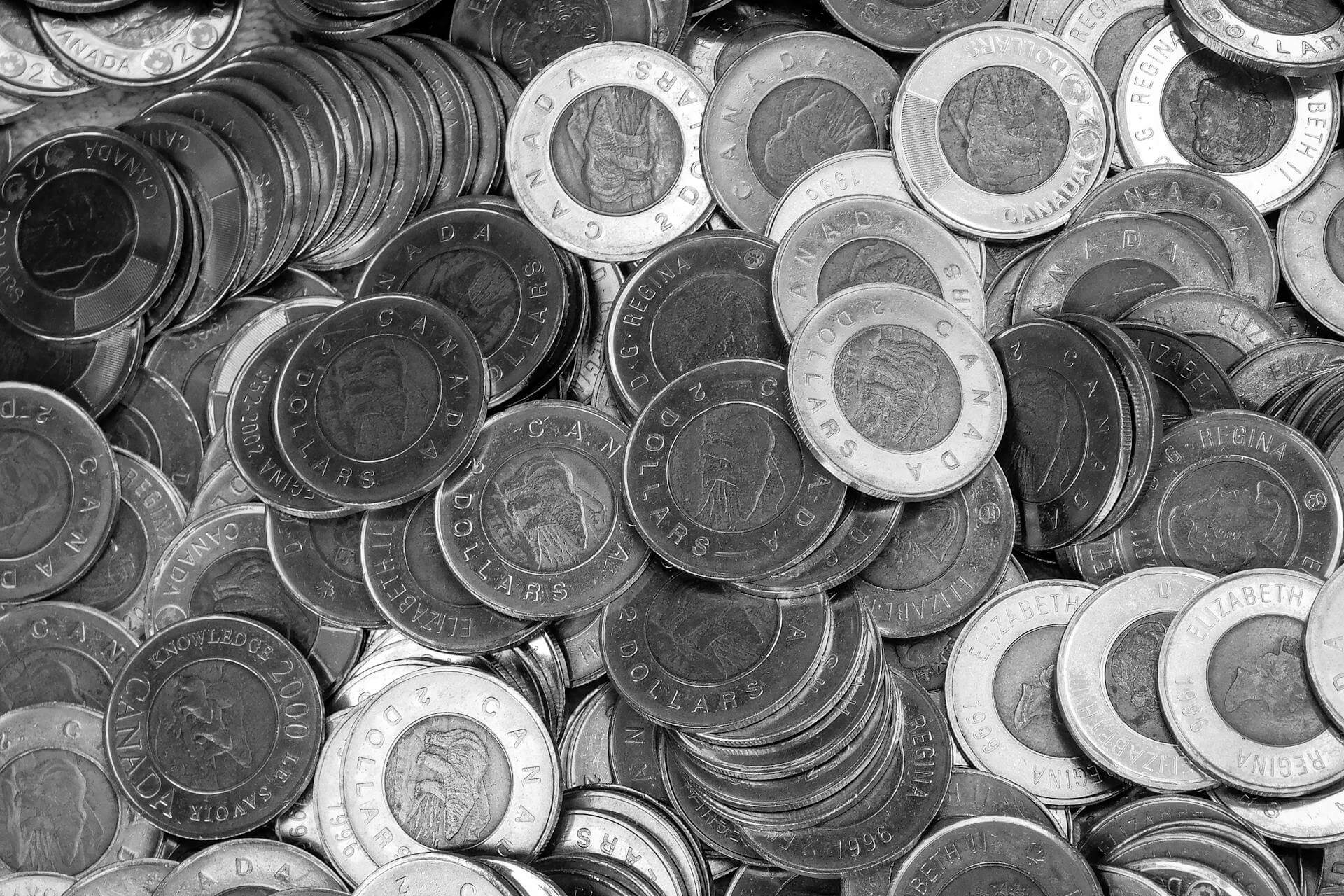 A black and white photo of a pile of Canadian $2 coins