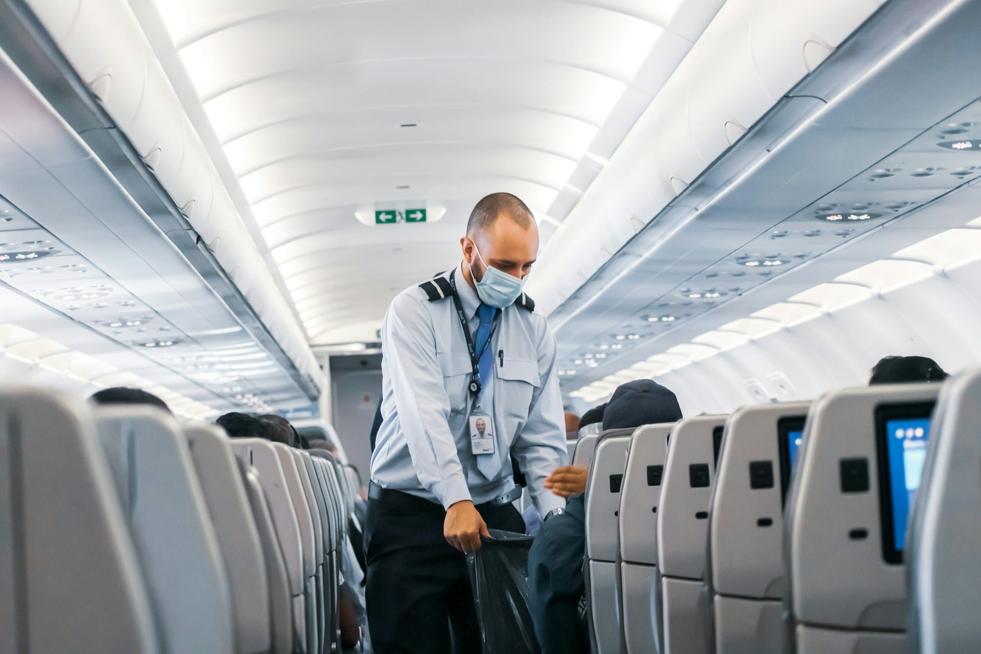 A flight attendant collects trash on a flight