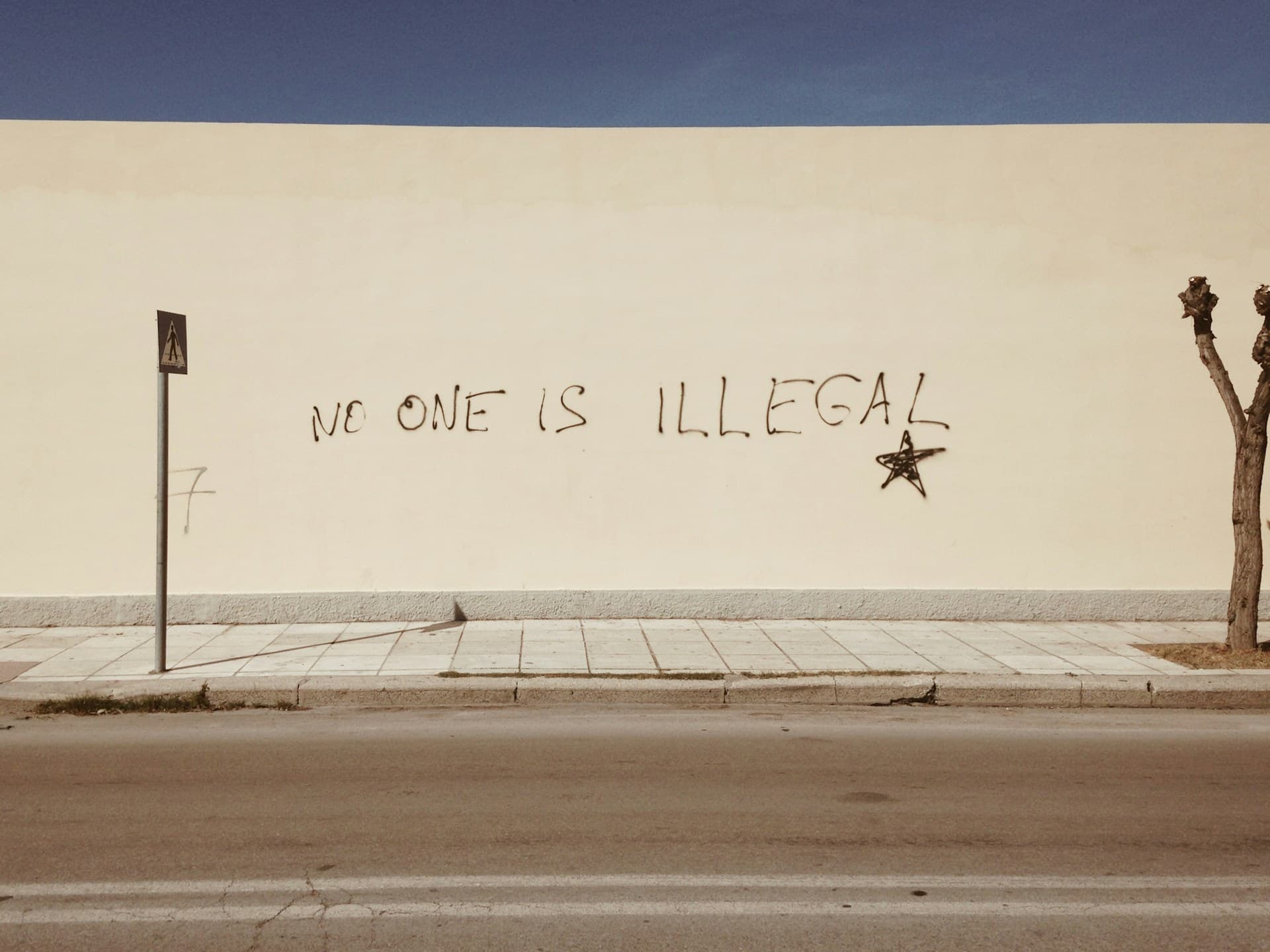 A wall with the phrase "No one is illegal" written on it
